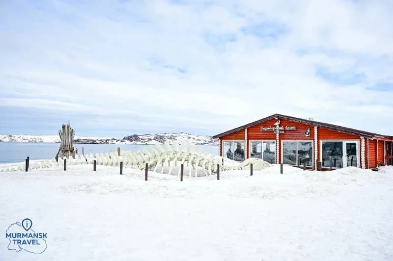 Red seaside building and snow-covered ground in Teriberka