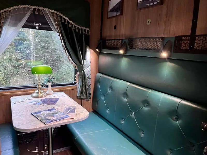 Green seating and a table inside a retro train